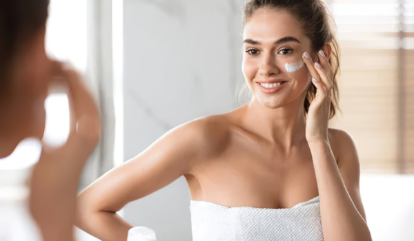Femme appliquant un soin du visage naturel devant un miroir